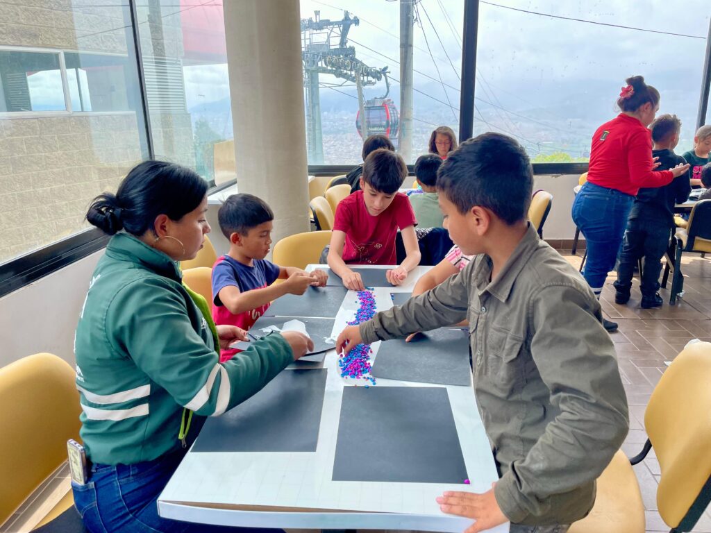 Niños haceiendo manualidades en el auditorio manitas en la graduación de Guardianes Junior de TransMiCable en Ciudad Bolívar