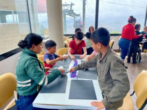 Niños haceiendo manualidades en el auditorio manitas en la graduación de Guardianes Junior de TransMiCable en Ciudad Bolívar
